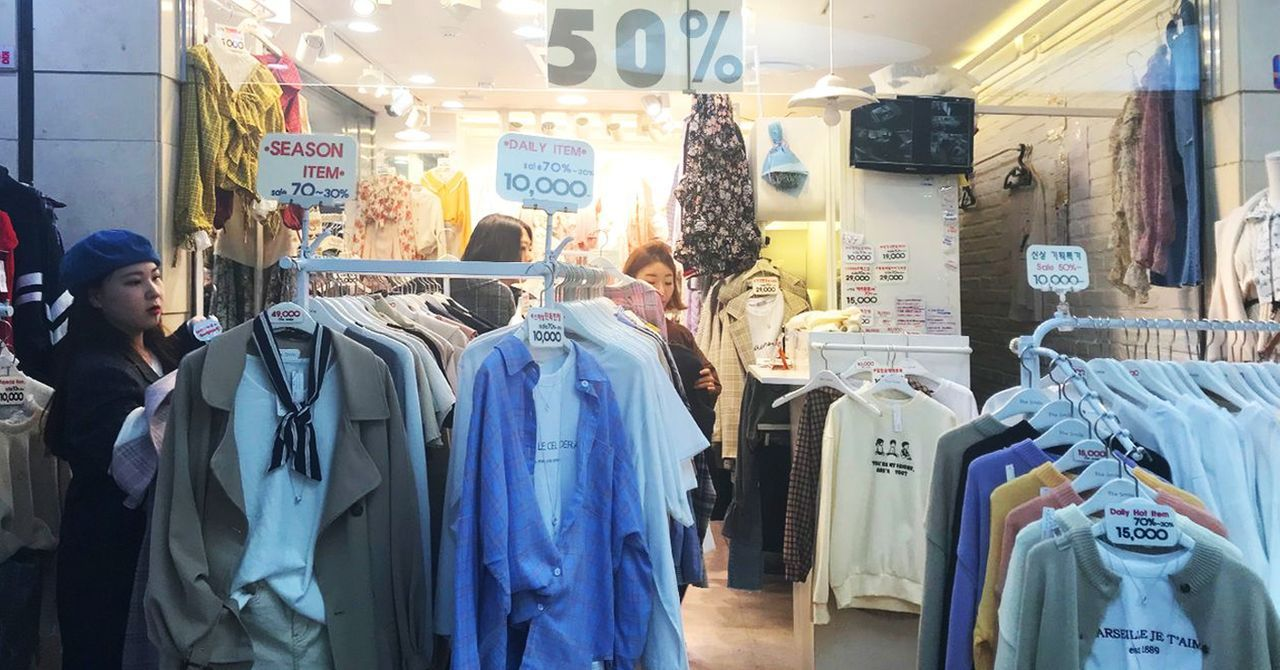 明洞商店內部服裝打折促銷，吸引大批顧客，展示韓國時尚流行趨勢和實惠價格。