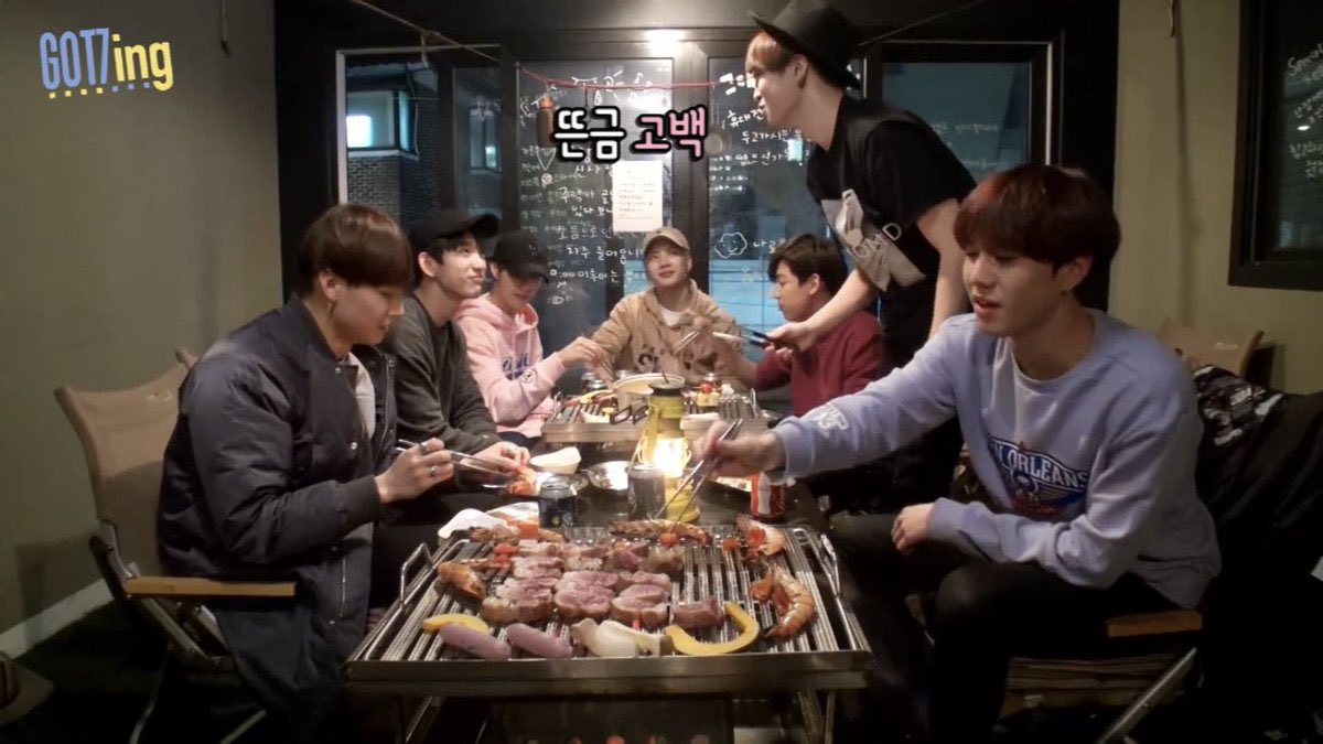 난장 캠프에서 그릴에 고기를 굽는 모습입니다. 창문 너머로는 고풍스러운 인테리어가 보입니다.