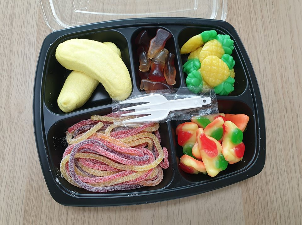 裝著不同形狀和顏色軟糖的便當盒，有香蕉造型軟糖和多彩糖果。