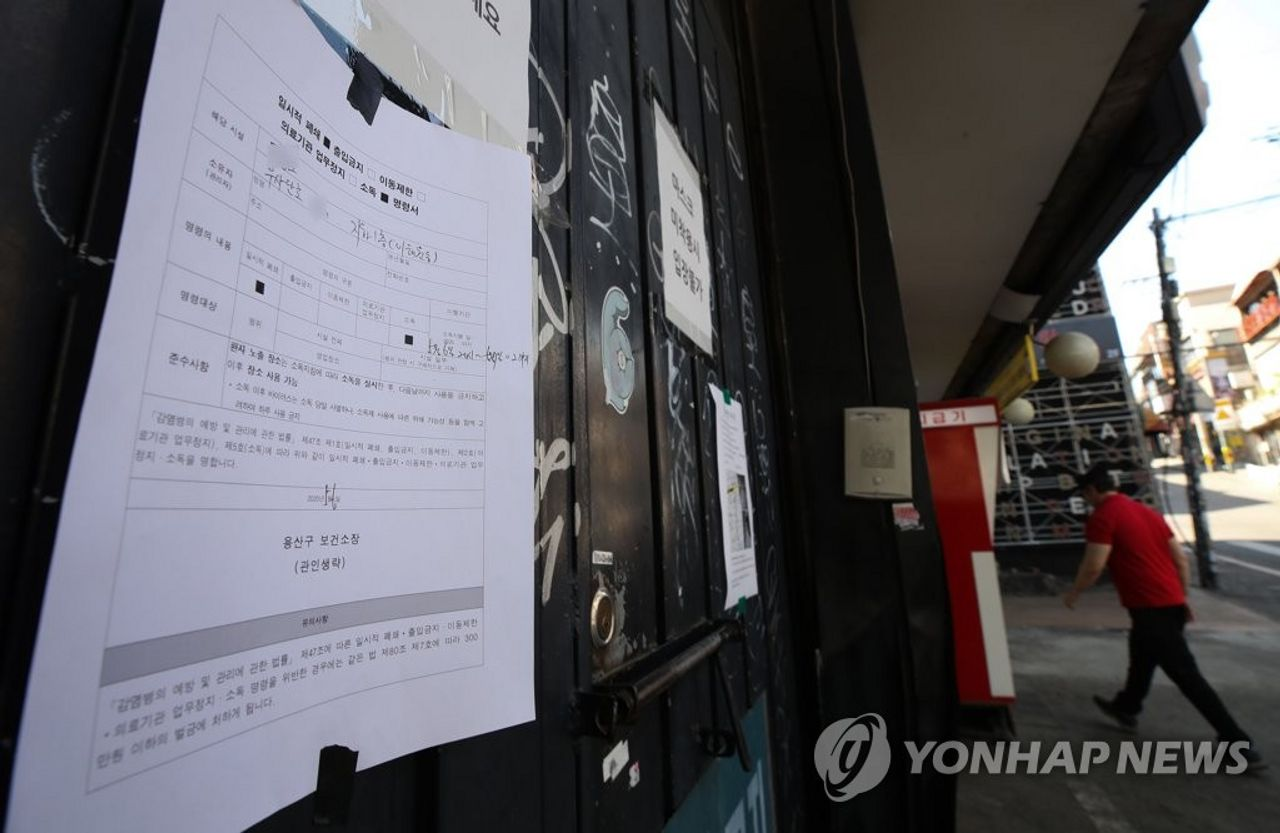 夜店大門貼著臨時關閉告示，顯示由於疫情影響暫停營業，門外行人戴著口罩經過。