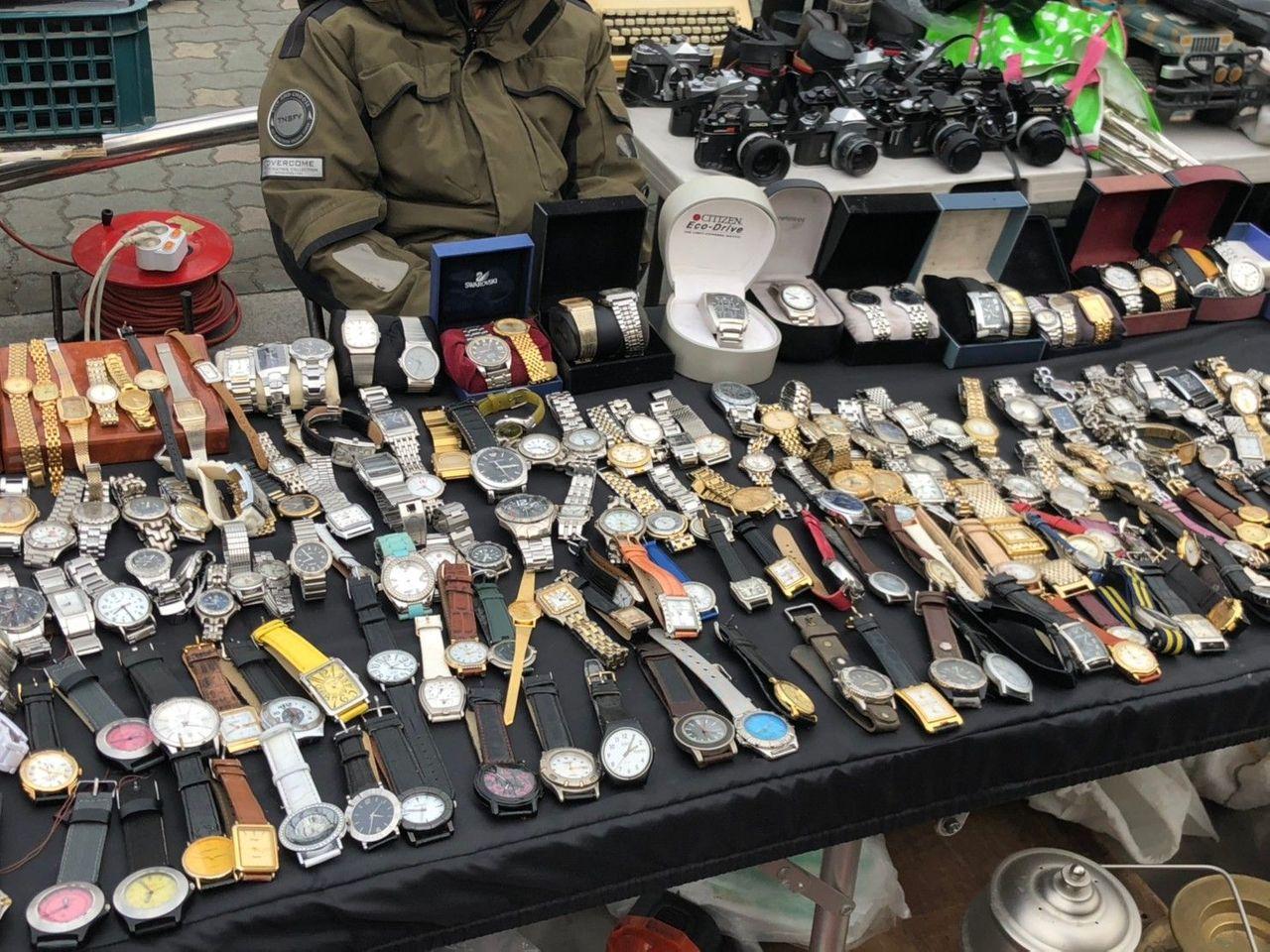 ภาพของนาฬิกาและกล้องถ่ายรูปที่แผงวางขายในตลาดมือสองดงมโย ใช้นาฬิกาเป็นประธาน