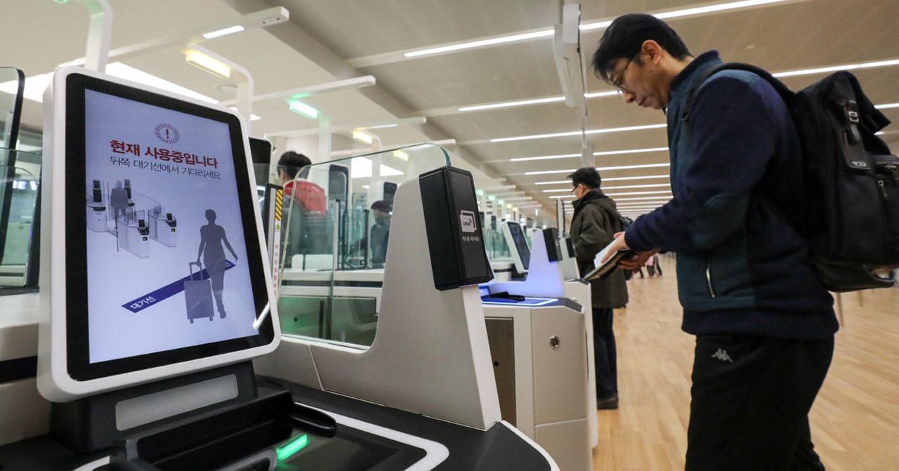 一名乘客在韓國機場讀取護照的自助服務過程，背景顯示防疫訊息。