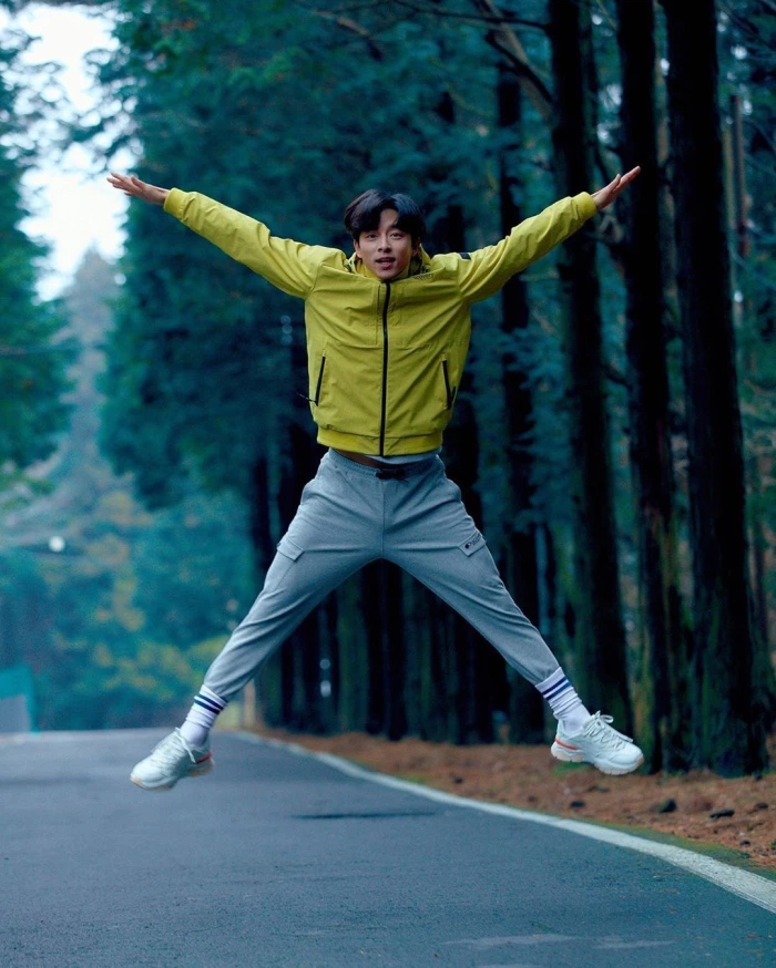 穿着绿色Discovery夹克的孔刘，在林中道路上系鞋带，展现了机敏而活力十足的户外风格。