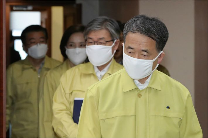 數名穿著黃色防護服的官員走出會議廳，象徵嚴肅的防疫決策。