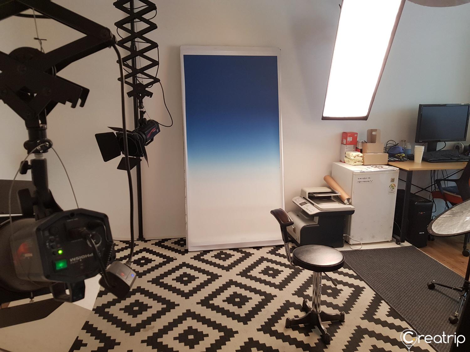 Comfortable living room with hardwood floors, audio equipment, and computer monitor in a stylish building of 포크스튜디오, a Korean photo studio.