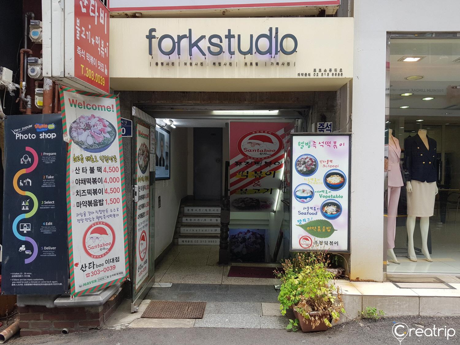 A retail building for 포크스튜디오 with a plant-filled facade and advertising logos.