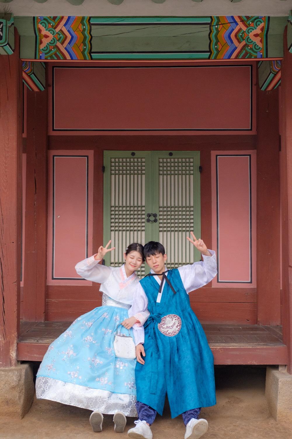 Smiling visitors wearing hanboks at Gyeongbokgung Palace, enjoying leisurely beauty of temple in various colors.