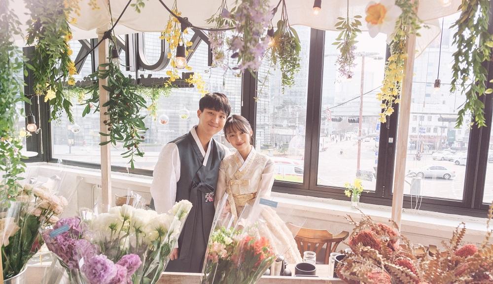 Image of woman in traditional Korean hanbok amidst flowers, at rental shop near Gyeongbokgung palace in Korea.