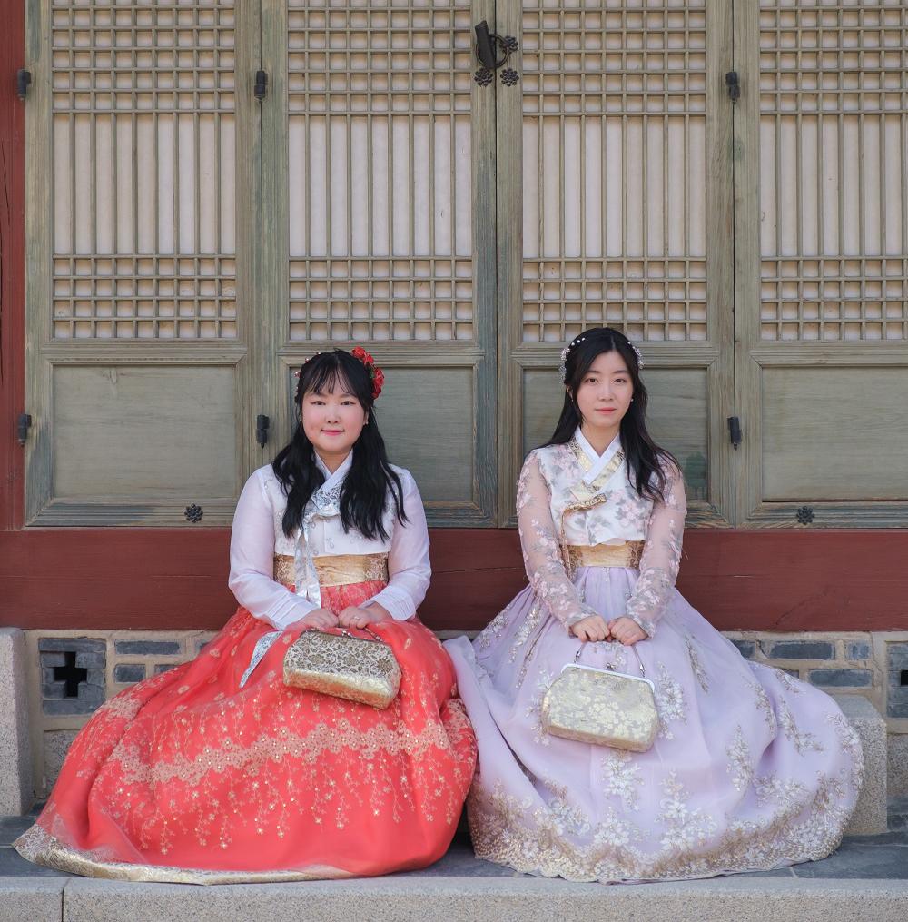 Smiling customers dressed in traditional attire at a hanbok rental shop near Gyeongbokgung Palace.