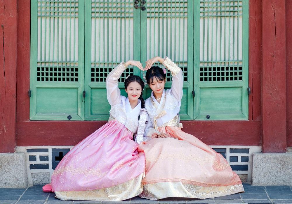 Smiling woman wearing a pink and magenta hanbok dress from Gyeongbokgung hanbok rental shop.
