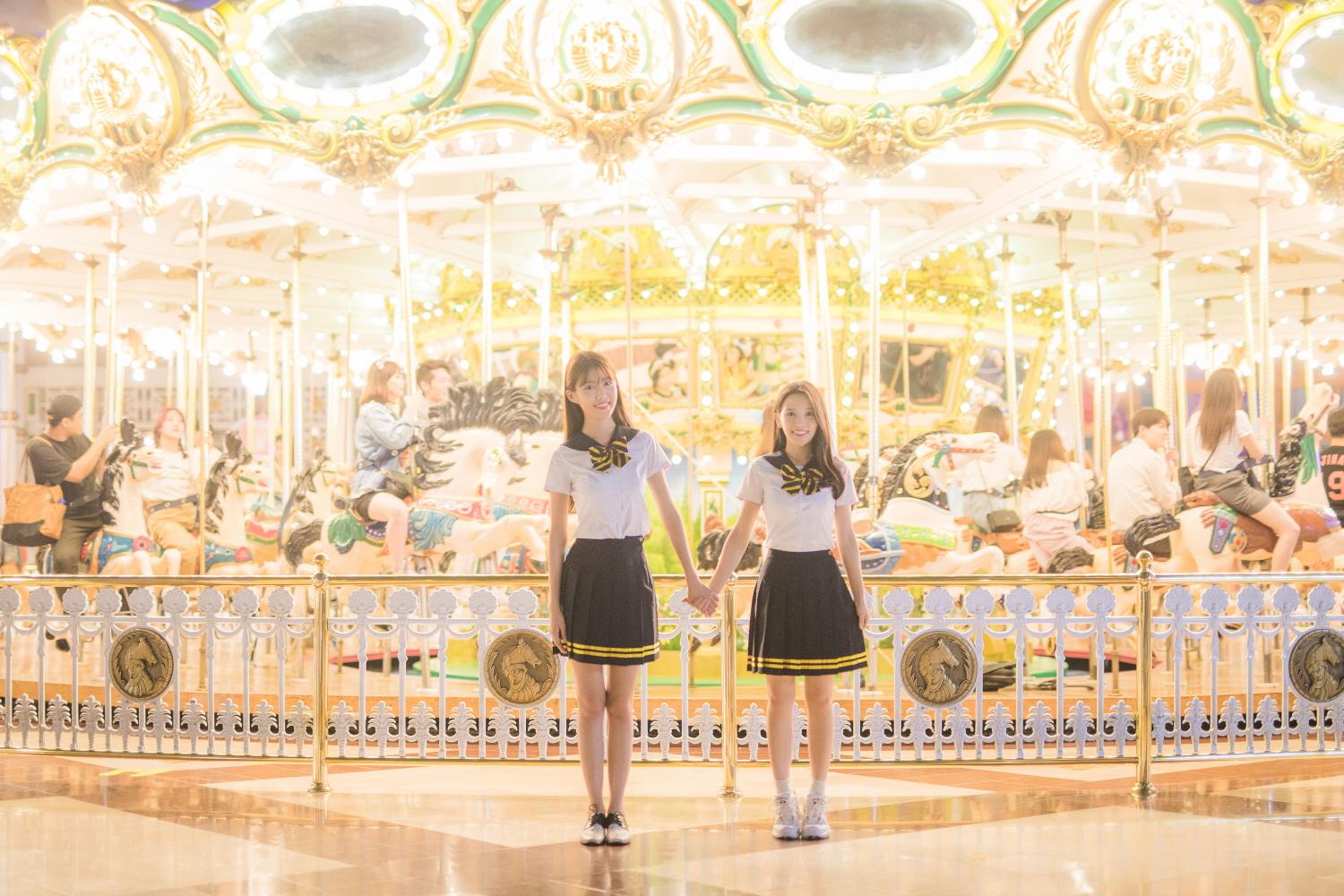 Group of people in Ewha school uniforms posing at a function hall amidst landmark city views.