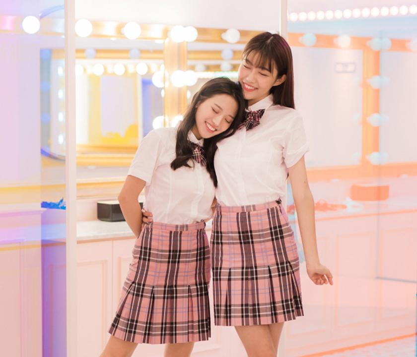 Smiling student models in Ewha school uniform with tartan skirt and plaid waistband.