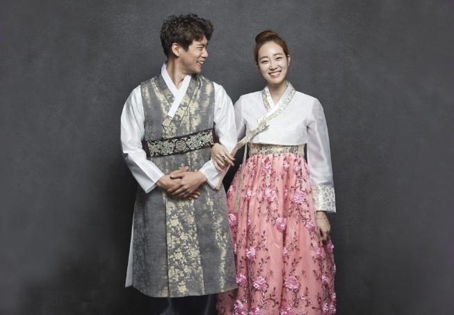 Smiling woman in traditional one-piece garment at Gyeongbokgung hanbok rental shop in Korea.