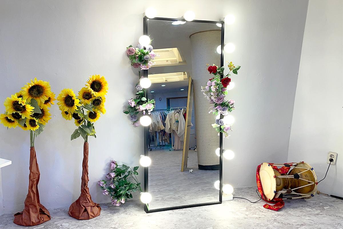 Colorful hanbok rentals surrounded by plants and flowers in Gyeongbokgung building interior with a drum and other musical instruments.