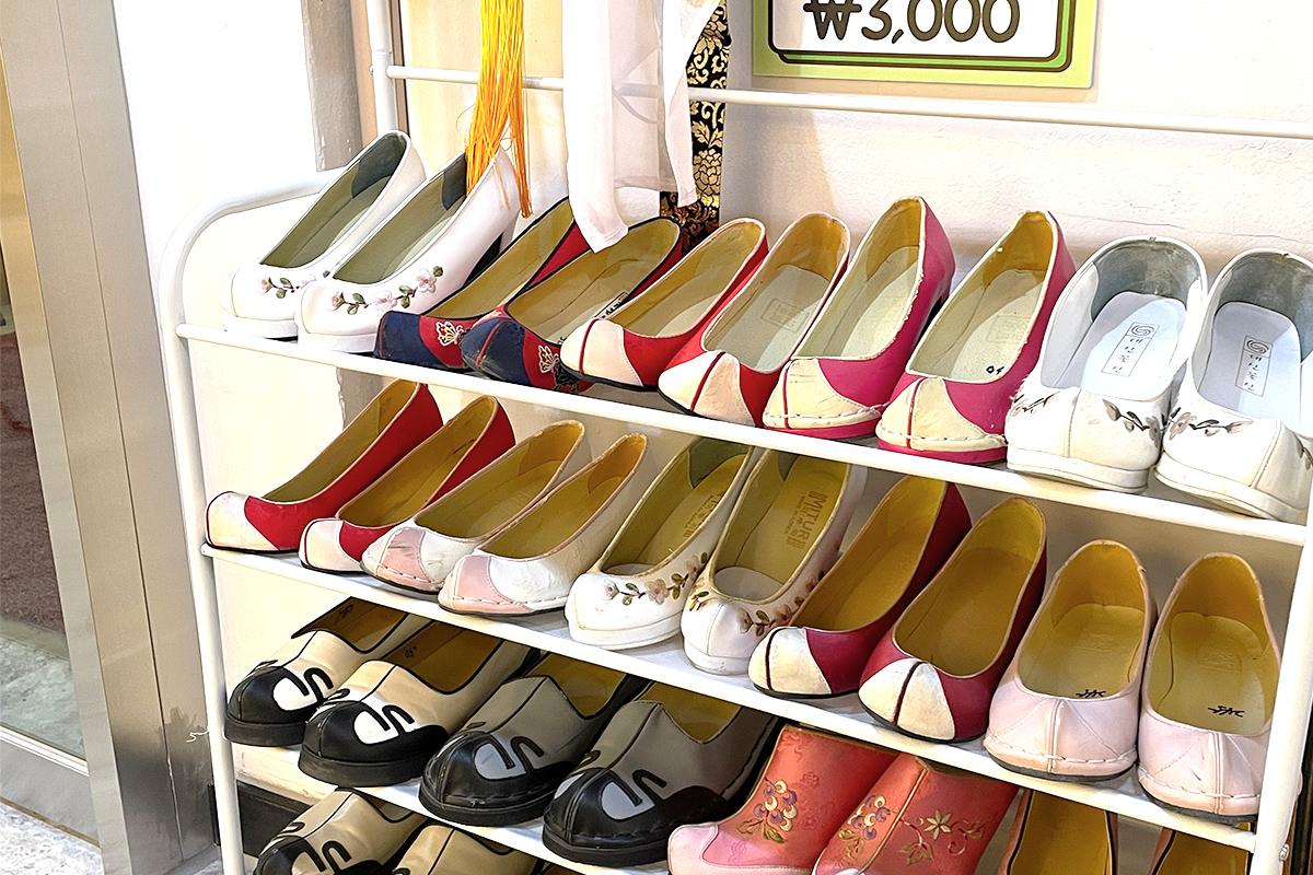 Red athletic shoes displayed on shelves in Gyeongbokgung hanbok rental shop, with shoe organizer and chair.