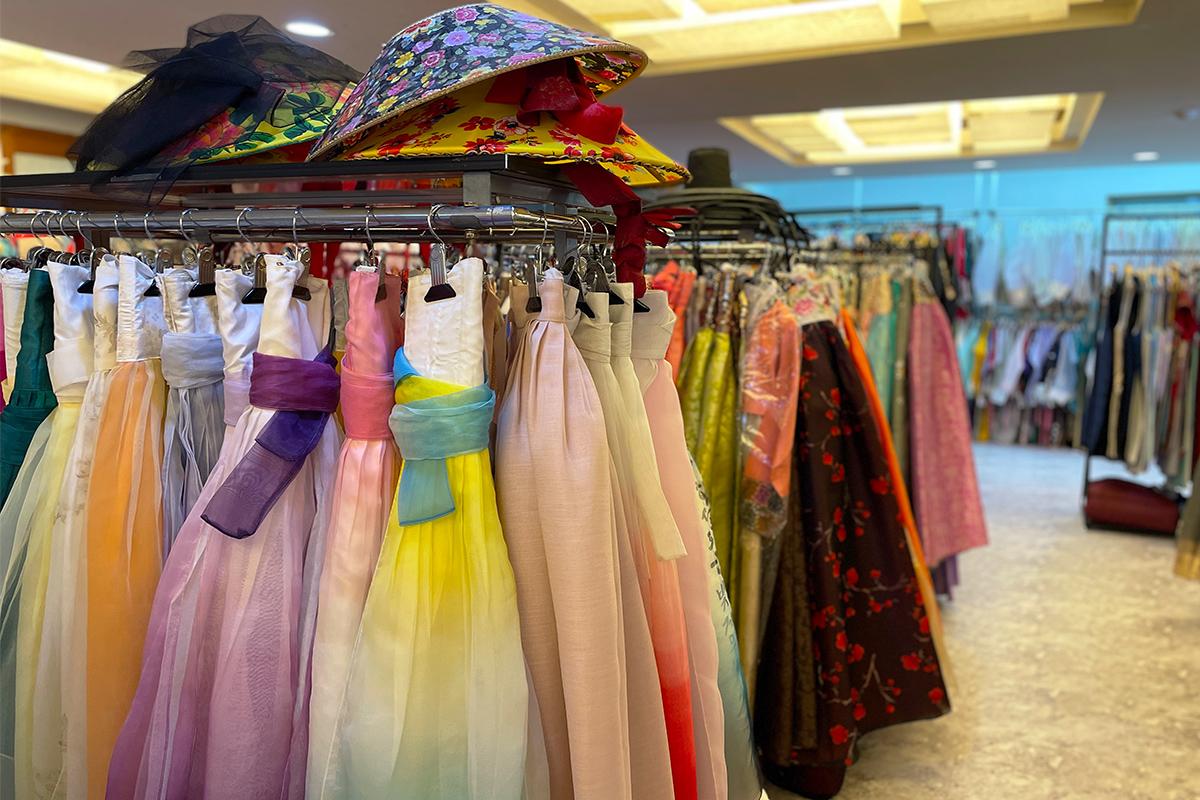 Hanbok rental shop display featuring magenta textile sleeves on hangers for retail shopping.