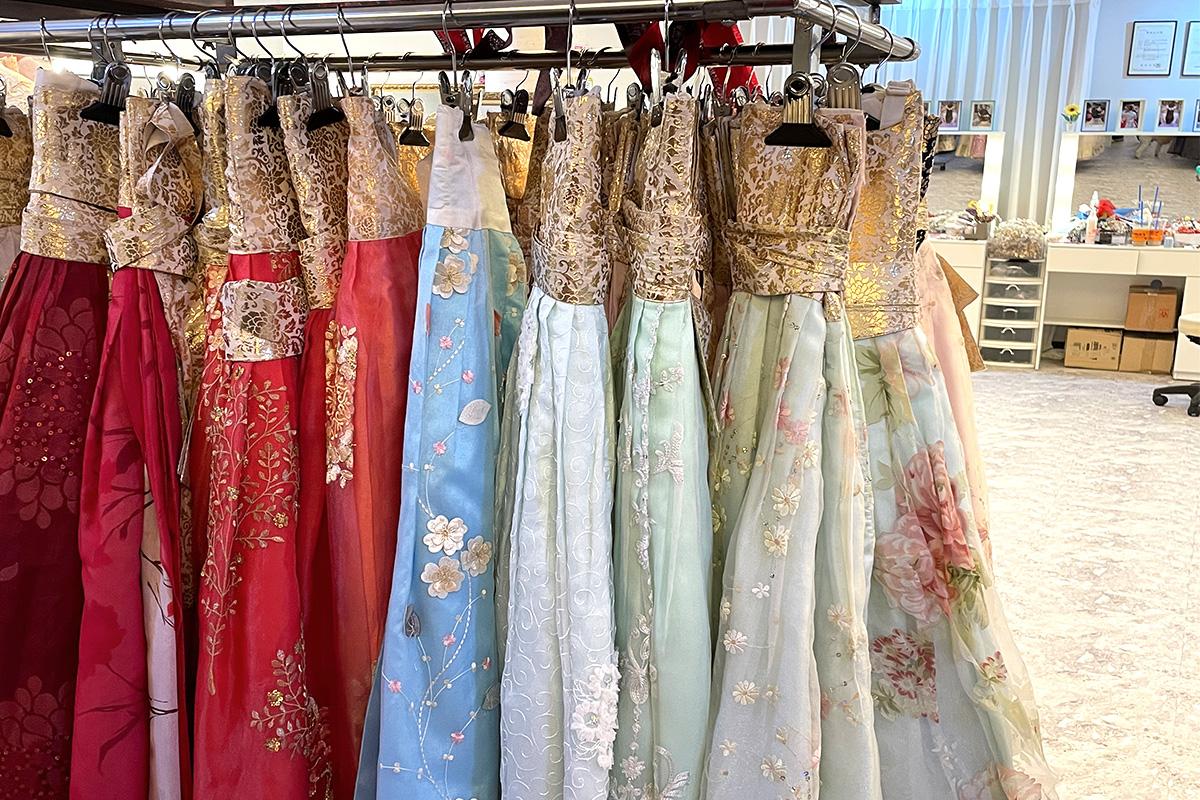 Hanbok dresses on a rack in a Korean boutique, including a colorful one-piece dress with sleeves, available for retail shopping.