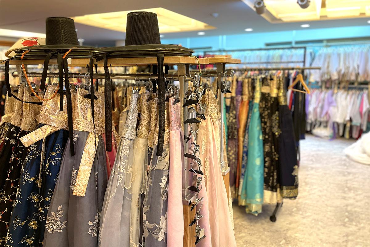 A metal clothes hanger displaying denim hanbok and fashion accessories in a Gyeongbokgung Hanbok boutique.