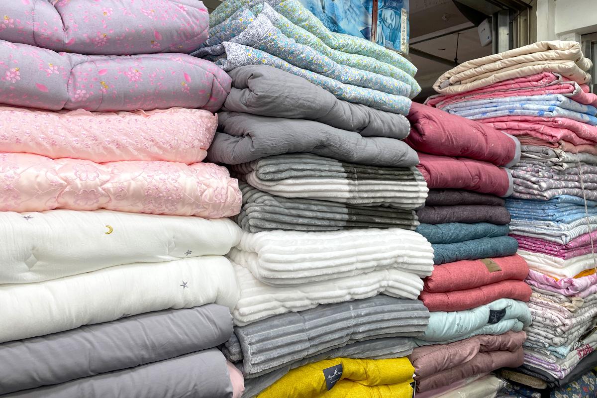 blue woolen textiles displayed in a marketplace stall at 광장시장 88호 아르페지오, a wooden retail hub in Korea.