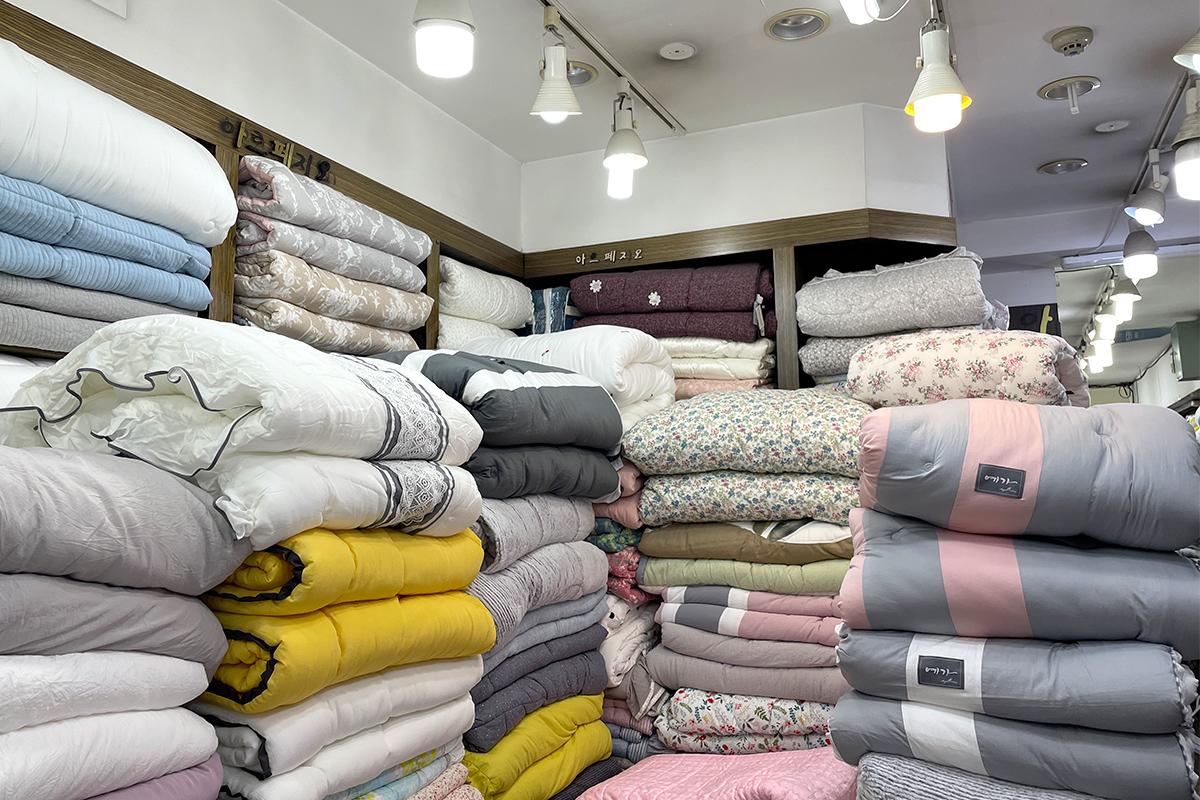 ceiling of Arpegeio 88 Market displaying textiles and linens in a room with wooden and composite materials in Carmine and wool fibers