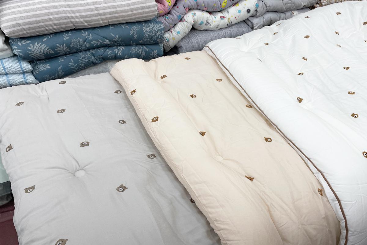 Wooden room interior with patterned linens, dress shirt, and bedding.