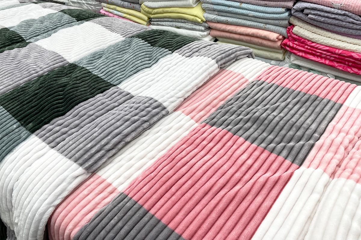 Artistic plaid patterned linens displayed in 광장시장 156호 아씨방, Korea on pink and magenta flooring.