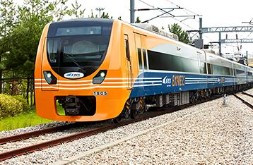 AREX train speeding through lush green landscape with blue sky and electricity poles in Korea.