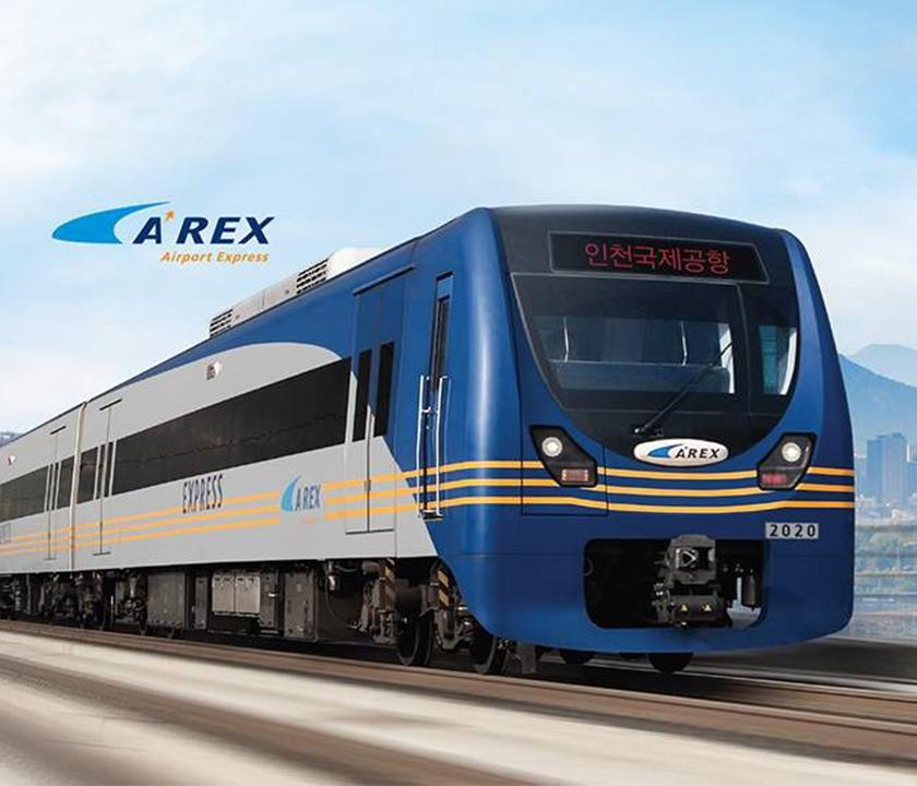 AREX train traveling under sky with clouds on railway track in Korea.