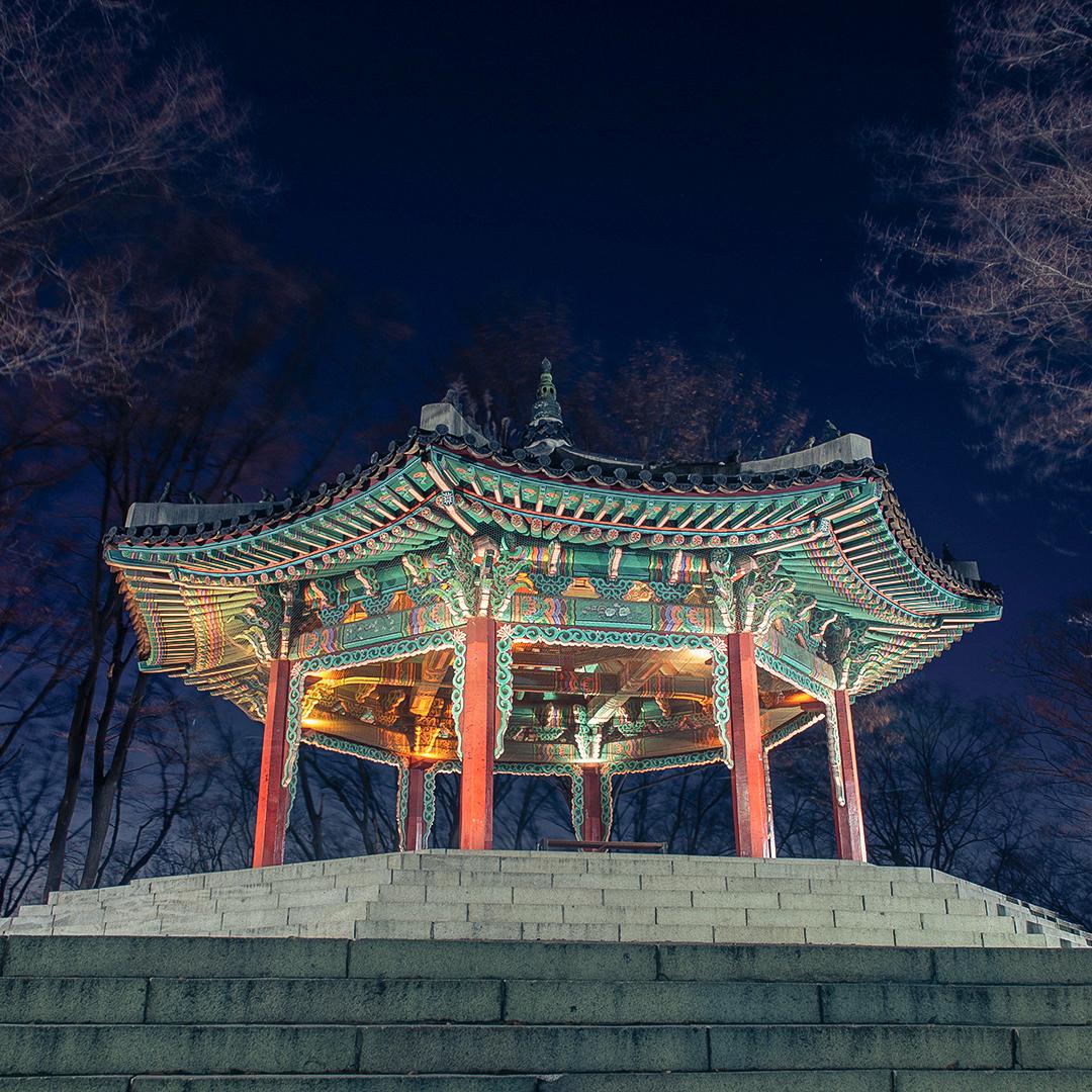 View from N Seoul Tower observation deck: Sky, clouds, trees, and temple style architecture.