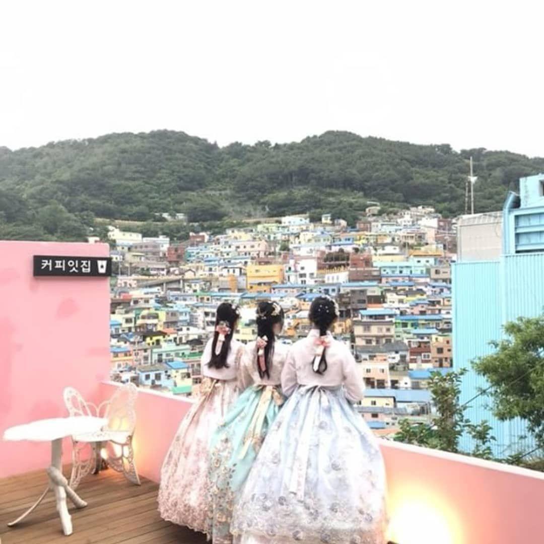 A view of Busan city skyline with traditional Korean houses and trees, highlighting Hanbok rental store and cultural events.