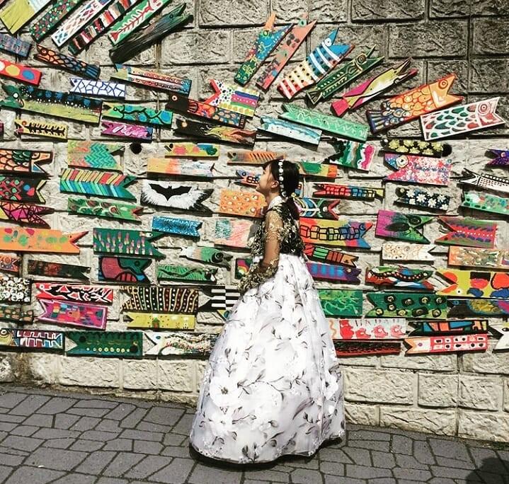 Public art installation in Busan showcasing traditional Korean textile patterns in a modern city setting with human activity.