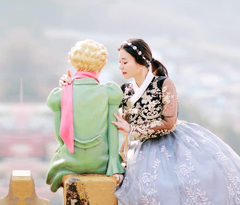 Korean traditional dress rental shop with people in nature wearing formal gowns for photoshoots.