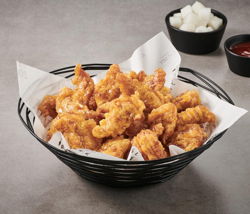 Delicious Korean fried chicken dish with crispy tender pieces, served on tableware with dipping sauce and ingredients.