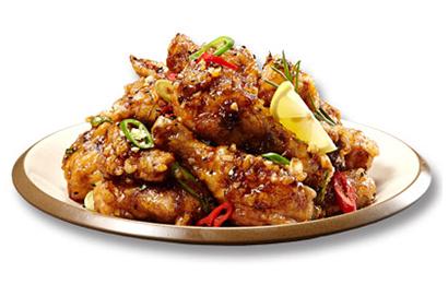 A savory dish of BHC chicken delivery, featuring crispy and flavorful yangnyeom chicken with a sweet and sour sauce, accompanied by a colorful assortment of fresh produce and vegetables.