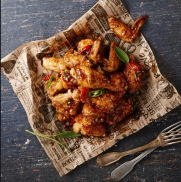A platter of BHC chicken delivery, spicy and savory, served with tableware and cutlery. Ingredients include fried chicken, leafy greens, and meat. Fast food recipe.