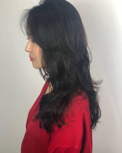 A hairstyle model stands in front of a Juno Hair salon, showcasing their brand. Visible features include lips, eyebrows, and a black shirt sleeve.