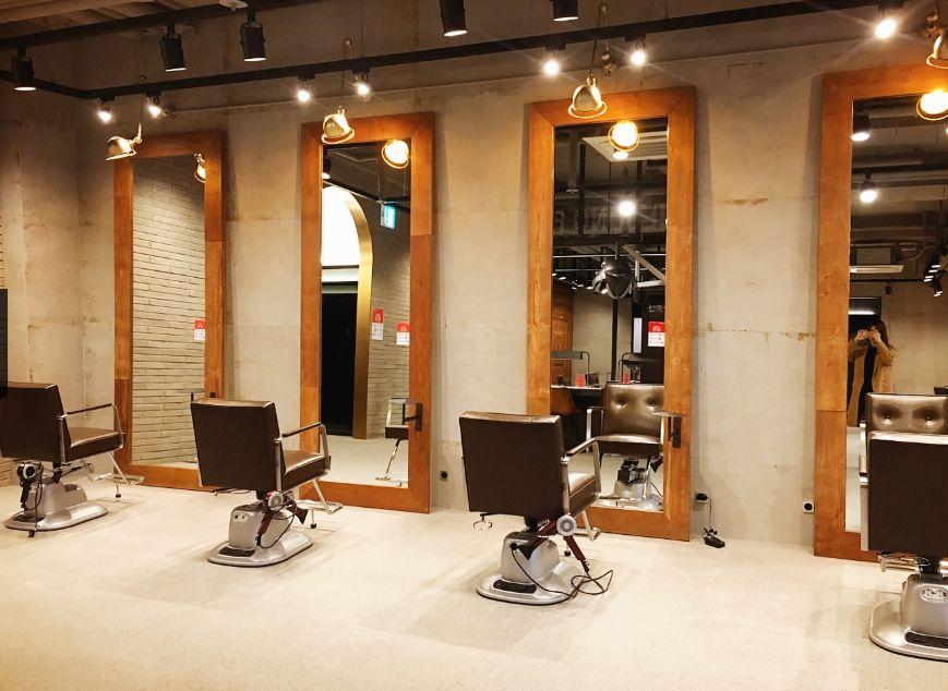 Juno Hair Hongdae station branch - interior of a modern hair salon featuring furniture, computers, and audio equipment.