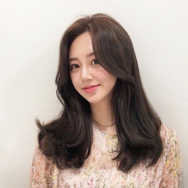 Model with a trendy hairstyle and a charming smile standing at the Juno Hair salon in Centum City, Busan. Focus on forehead, skin, lip, and chin.