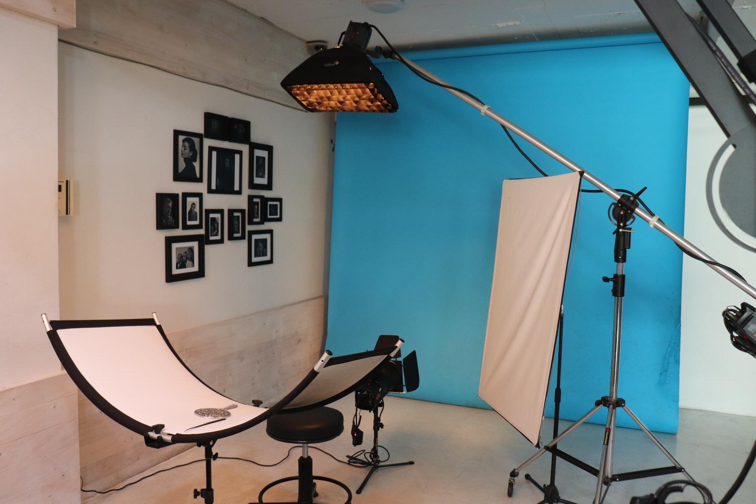 Interior of 우리동네사진관 Hongdae branch with wood flooring, ceiling, and tripod lamp for events.