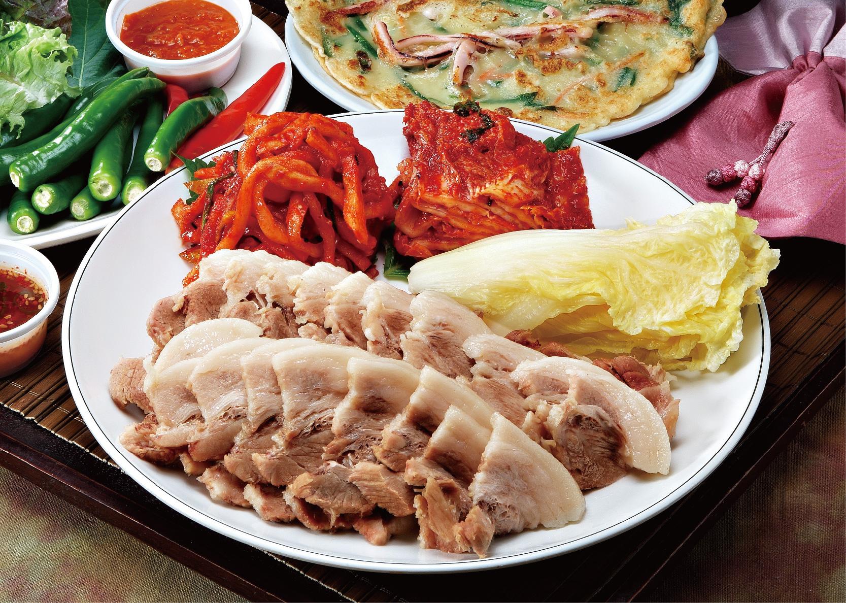 Plate of Korean cuisine featuring jokbal and bossam, available for delivery with tableware and ingredients.