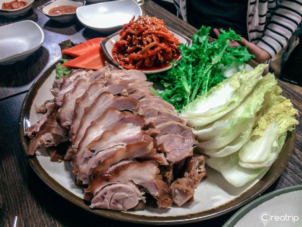 A platter of Korean-style pork trotters and sliced pork belly, with various side dishes and condiments, ready for delivery.