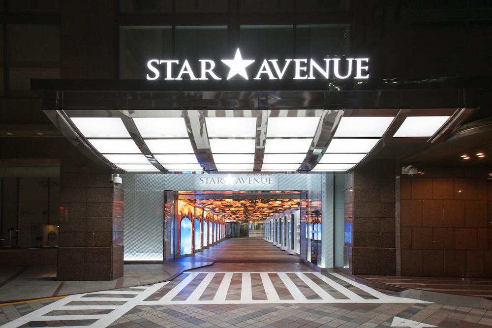Exterior view of temporarily closed Lotte Duty Free building with symmetrical facade, metal and glass fixtures, and dark flooring in city context.