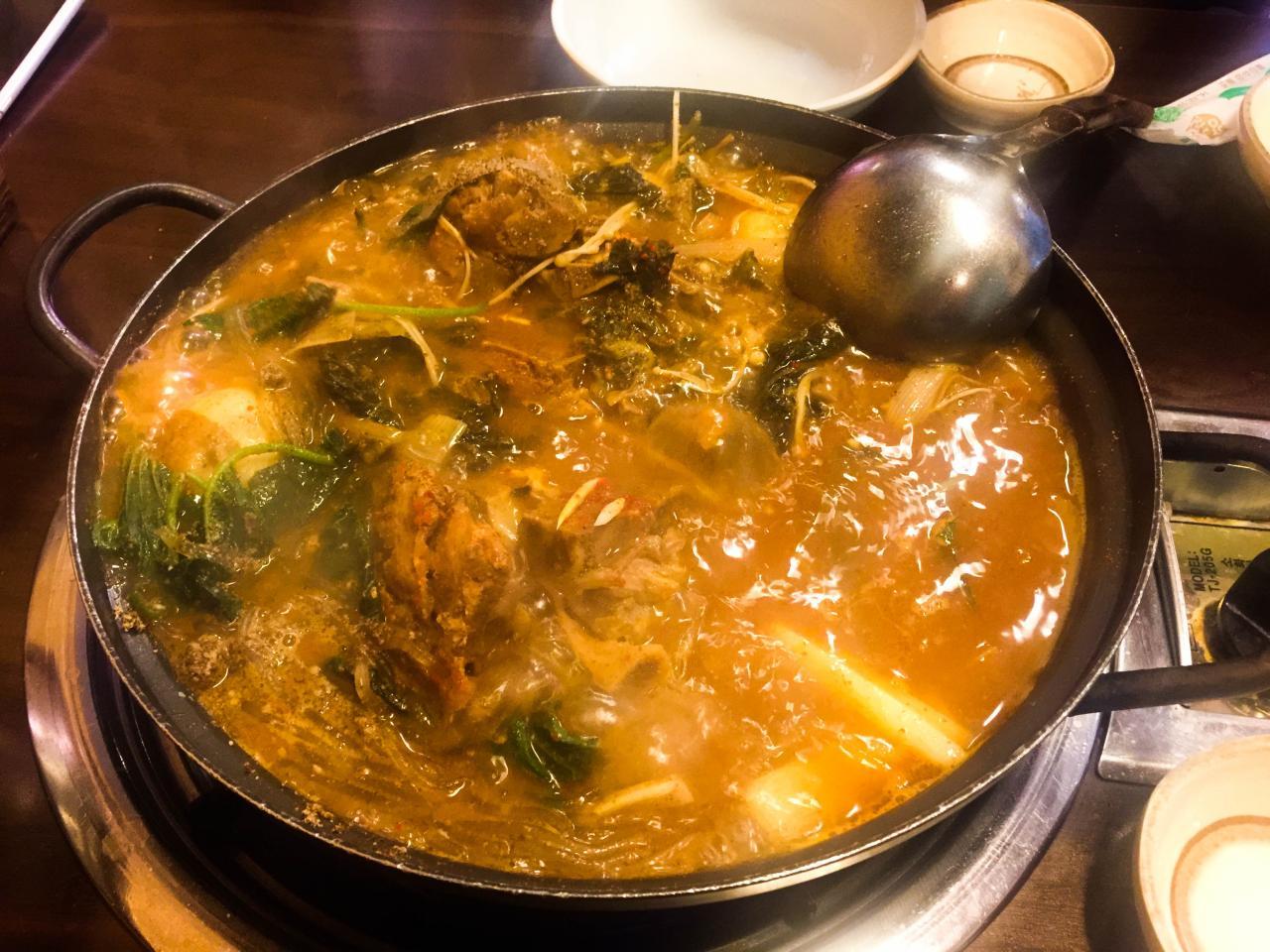 A steaming pot of 성균관 감자탕, a Korean stew filled with seafood, vegetables and spices.