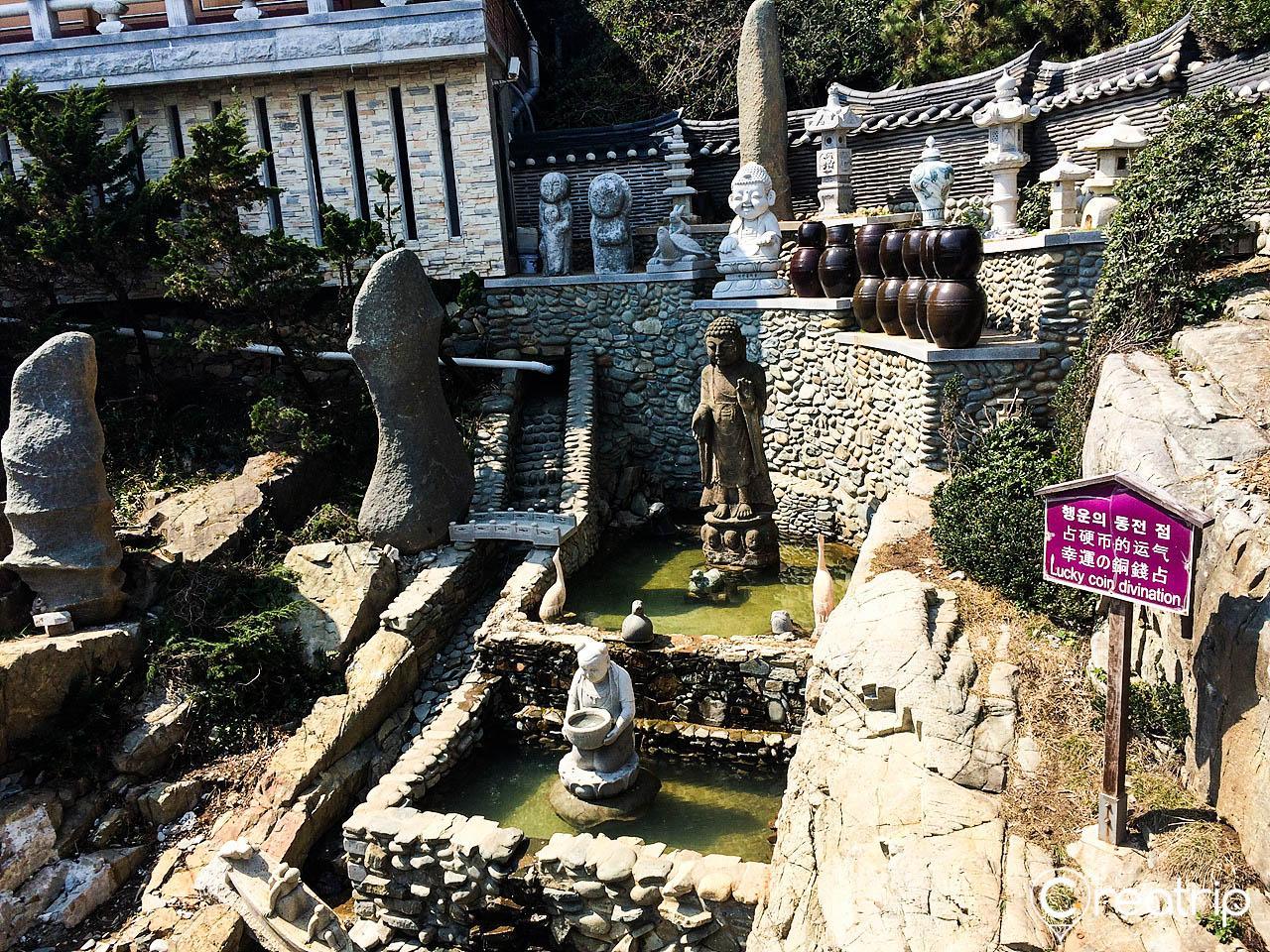 Scenic view of Haedong Yonggungsa Temple in Busan, featuring ancient architecture and lush green plants.