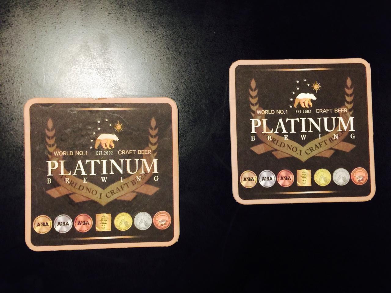 Cup sleeve of 리퀴드랩, a Korean craft beer brewery depicted on a metal emblem with a rectangle border. The emblem is displayed on the outside signage of a 맥주집 or beer house.