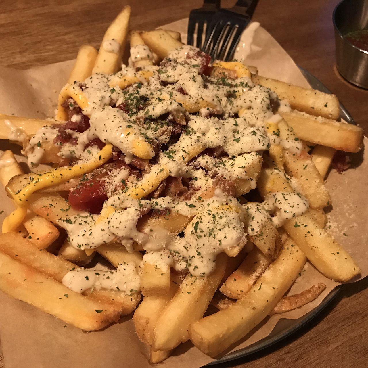 Liquid Lab's savory pub fare and wood tableware featuring tasty staples like Mostaccioli, served with fresh produce and kitchen utensils for a comforting meal.