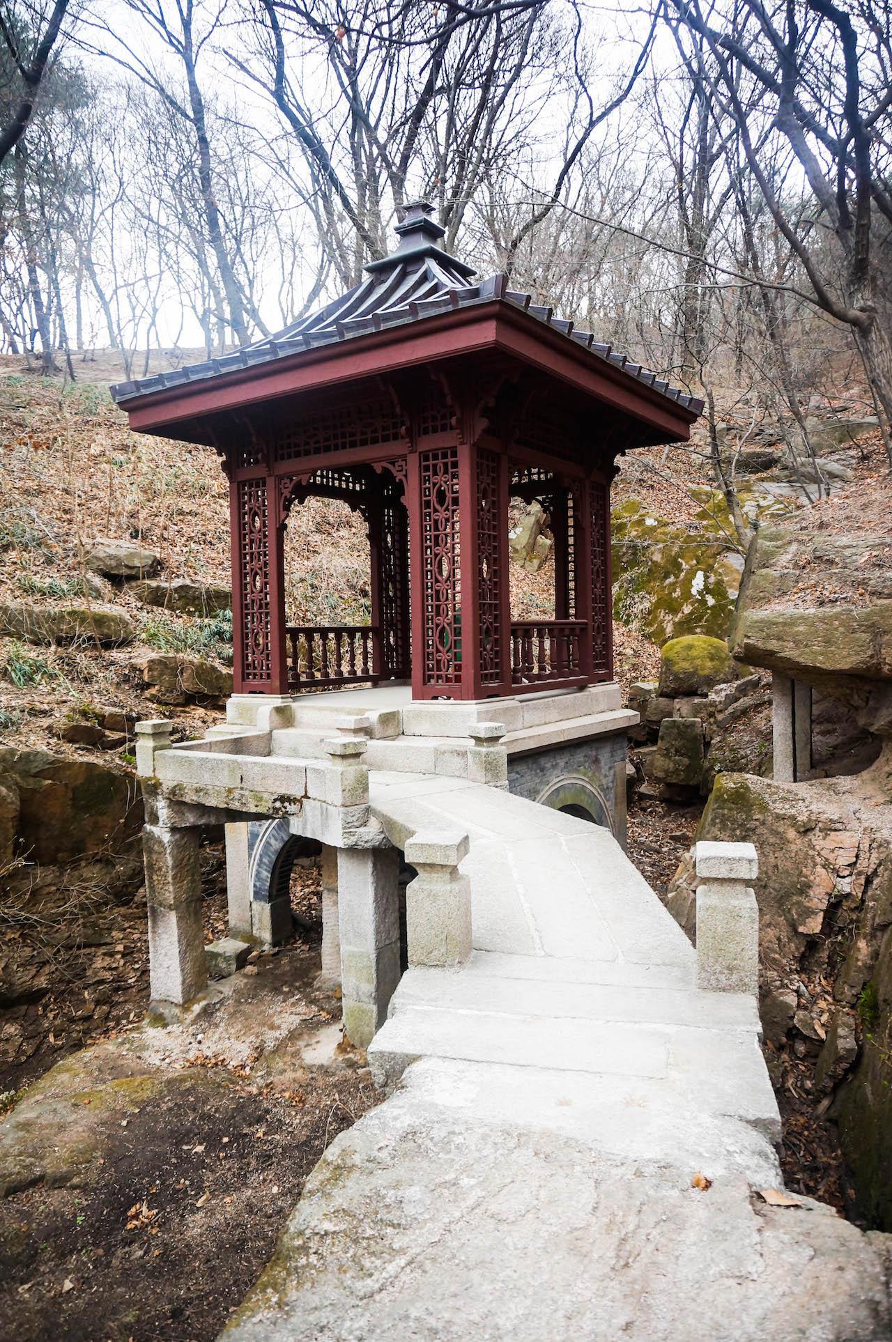 Stone steps lead up to the traditional temple of Seokpajeong, nestled amidst trees and a rural landscape.