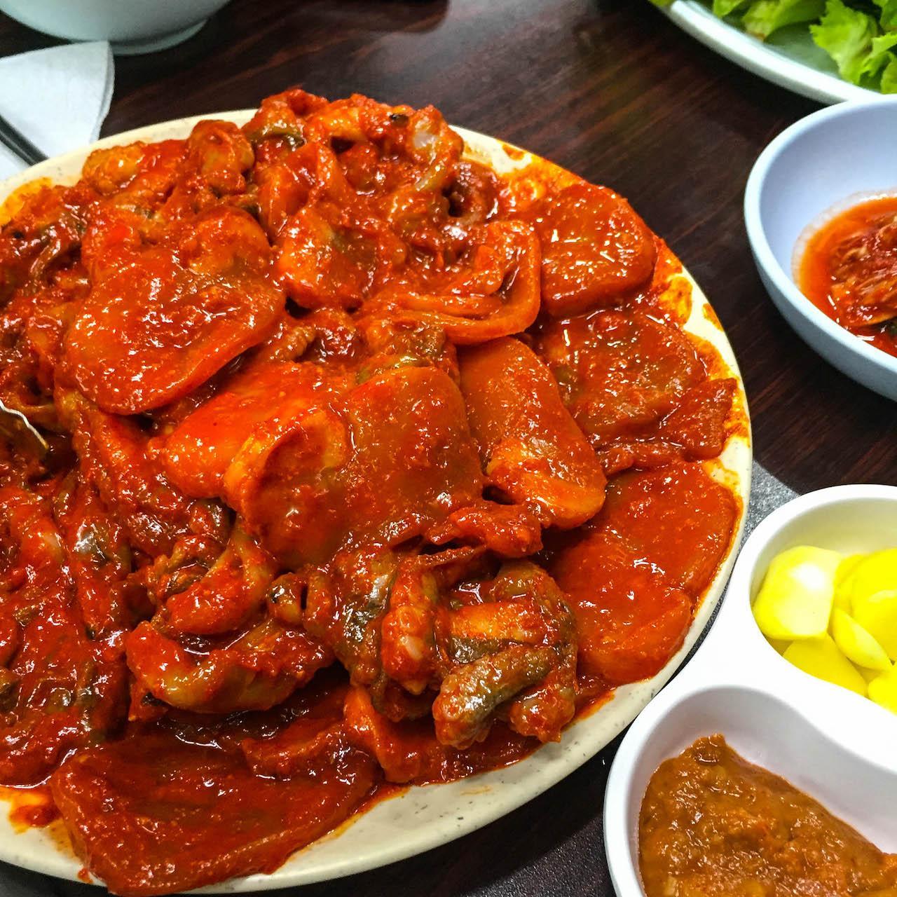 a dish of spicy to be grilled squid and beef served with rice and condiments on a plate.