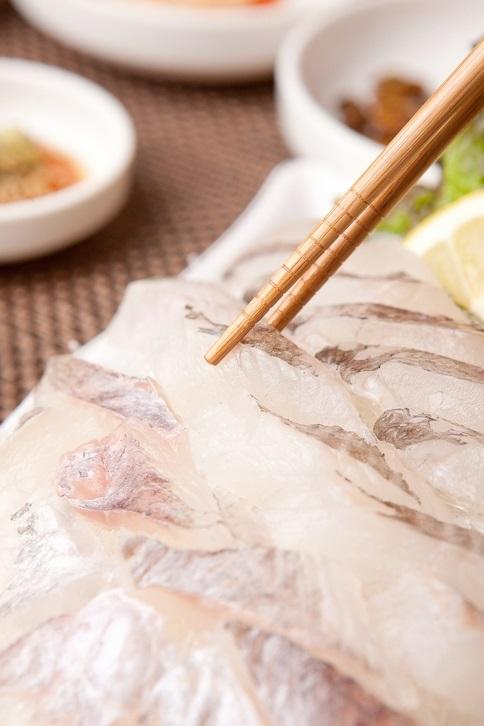 A wood table with traditional Korean seafood dishes at a lively restaurant in Noryangjin Fish Market.