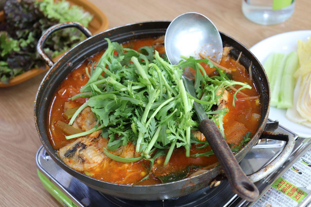Spicy seafood stew and side dishes on a table at a Korean restaurant in Noryangjin Fish Market.
